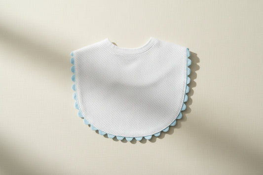 White bib with blue trim on a wooden surface