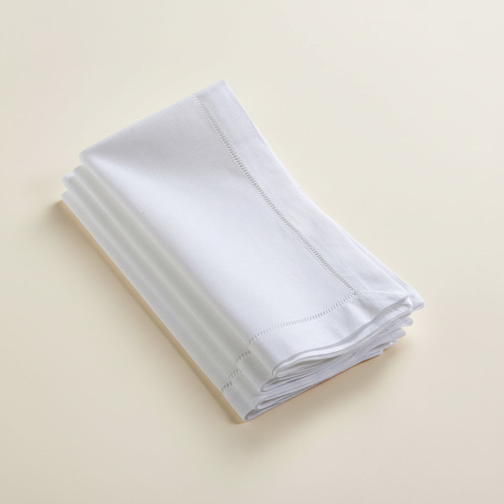 Stack of white hemstitch napkins on a white background
