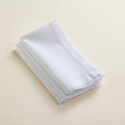 Stack of white hemstitch napkins on a white background