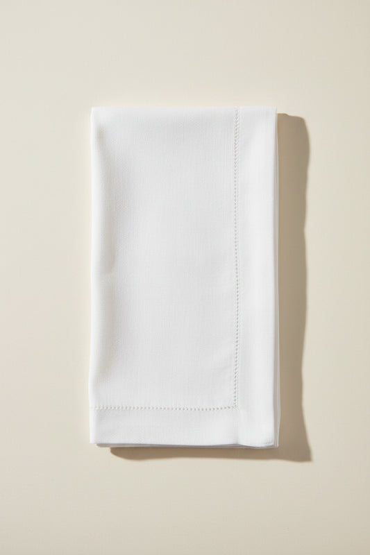 White hemstitch dinner napkin on a white background