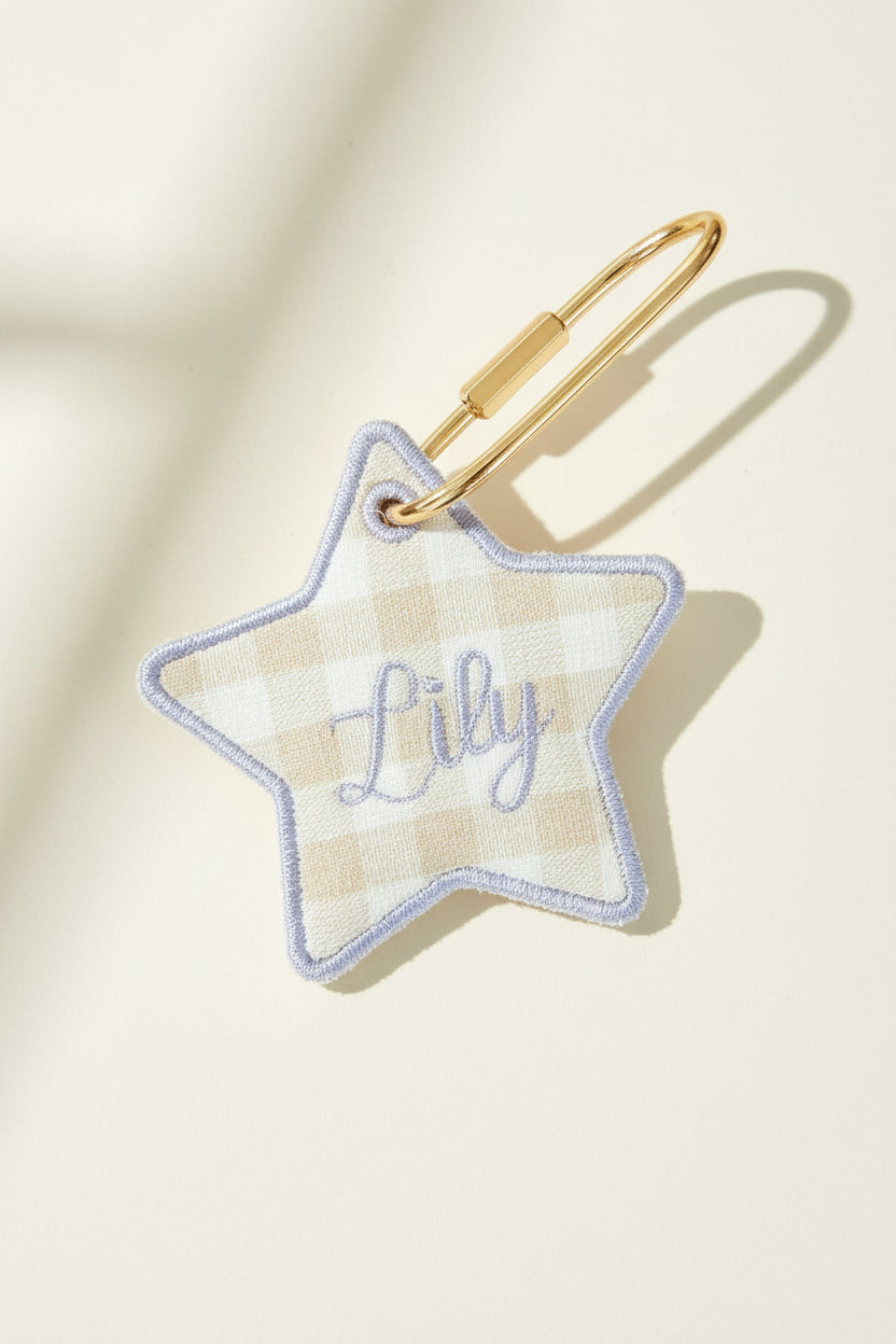 Star-shaped keychain with name embroidery on a beige surface