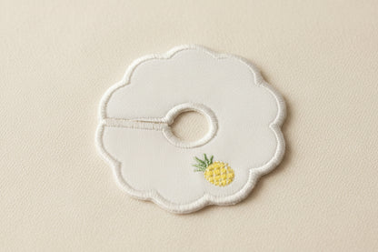 scalloped patch with pineapple embroidery on a beige background