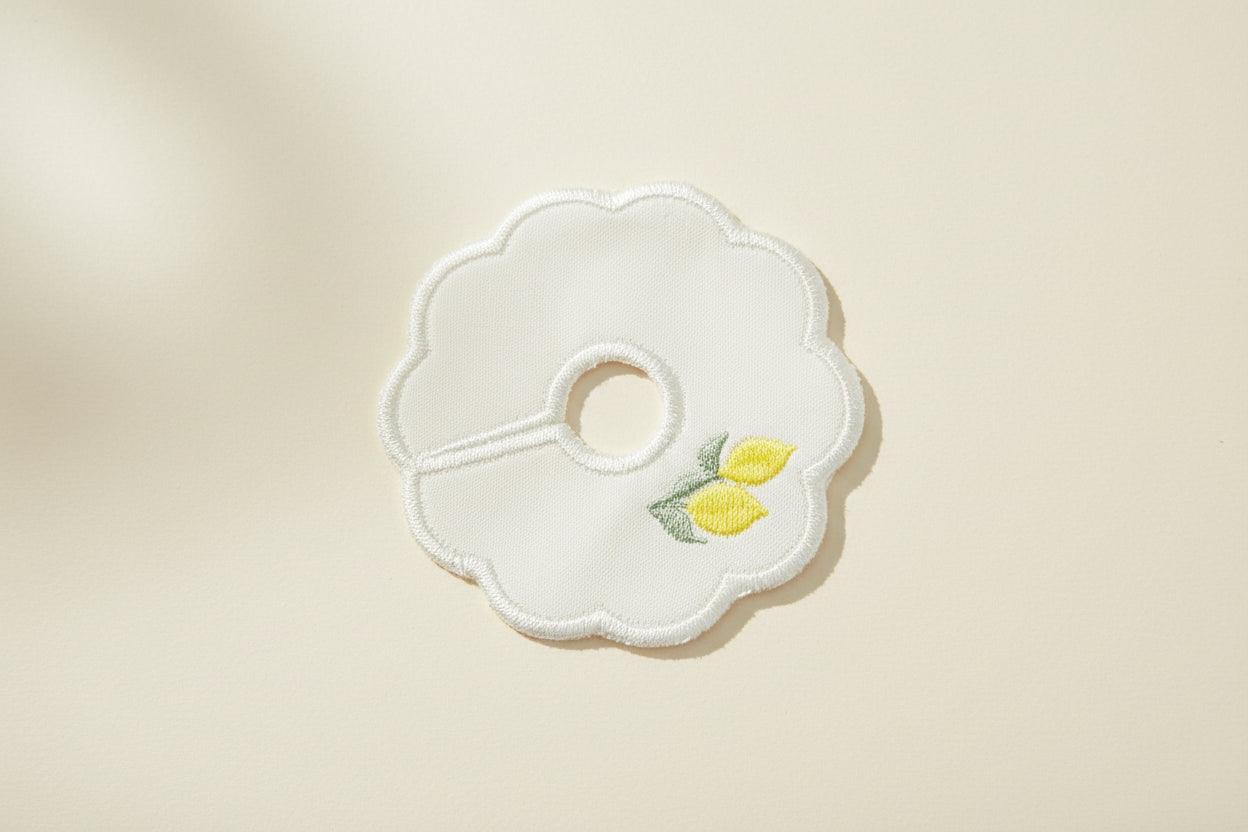 White embroidered patch with embroidered lemons design on a beige background