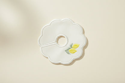 White embroidered patch with embroidered lemons design on a beige background