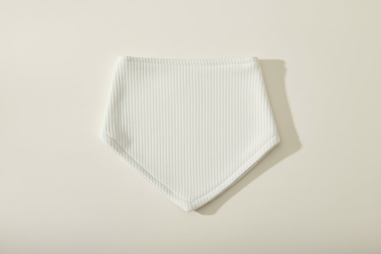 green baby bib on a warm white background