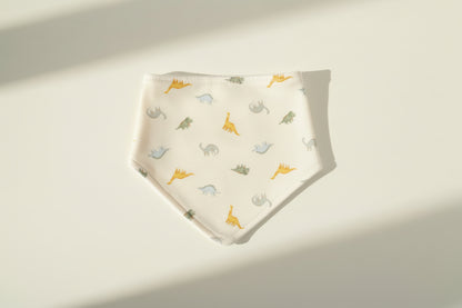 Baby bib with dinosaur pattern on a warm white background