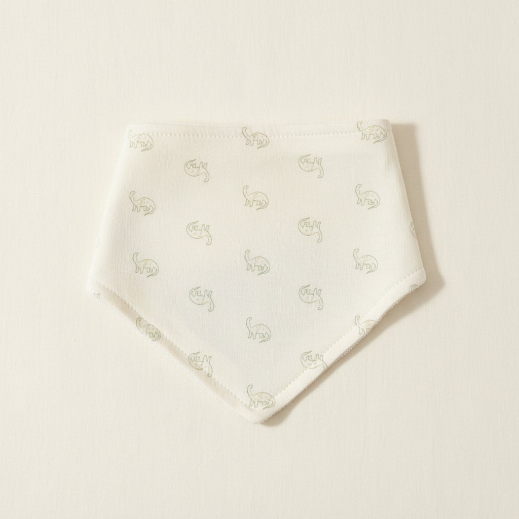 White baby bib with dinosaur designs on a warm white background 