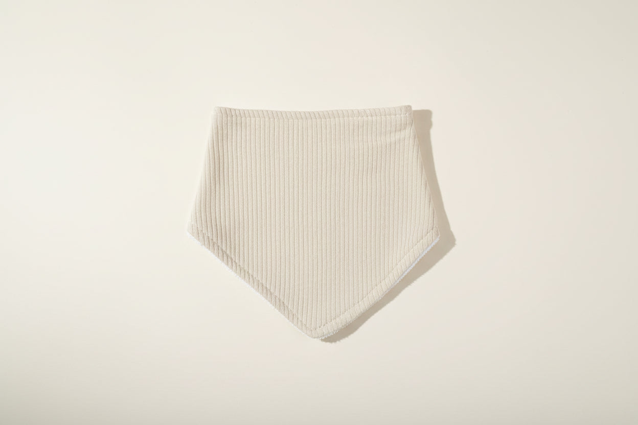 Light sage green baby bib on a warm white background.