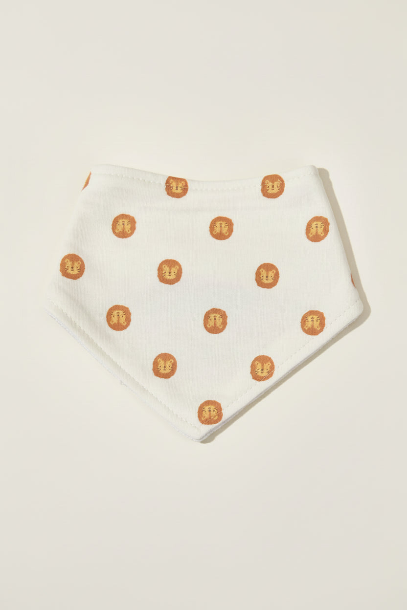 White baby bib with lion pattern on a warm white background.