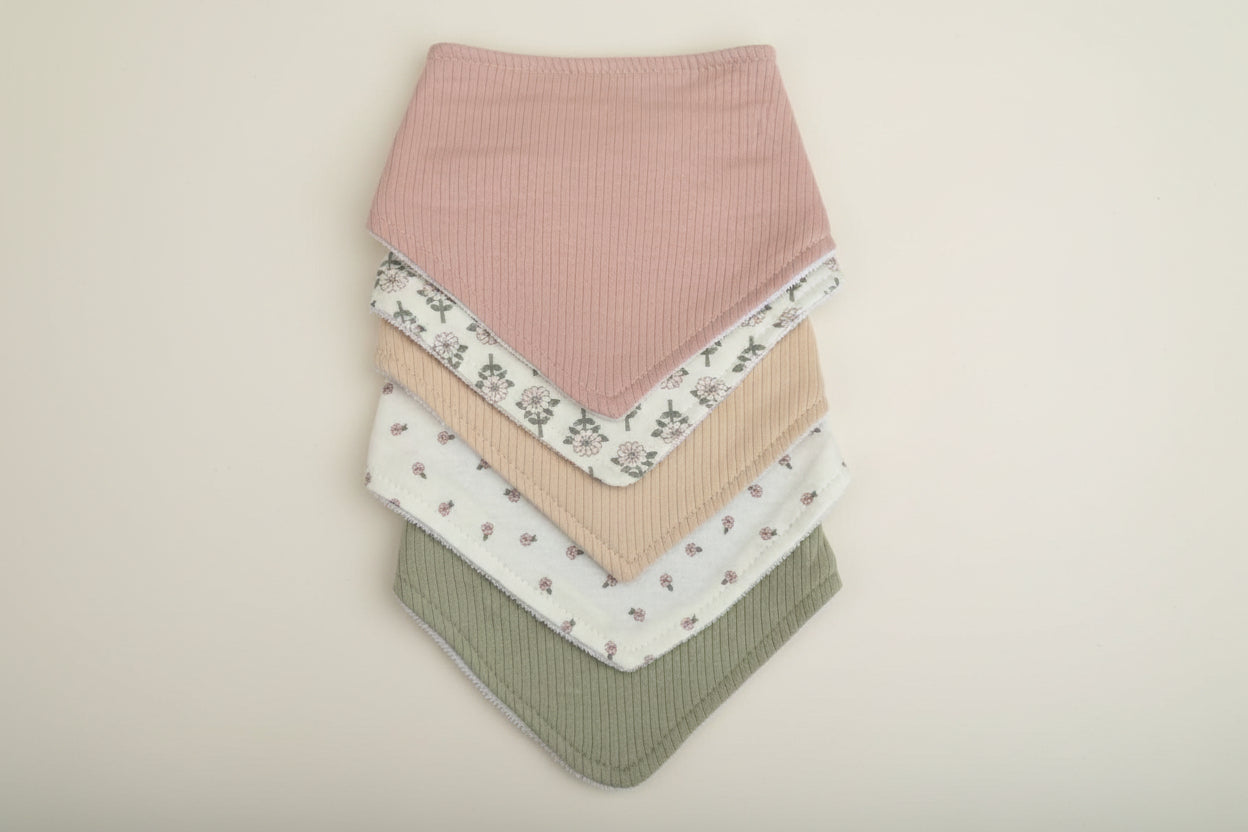 Set of 5 of colorful baby bibs on a warm white background.