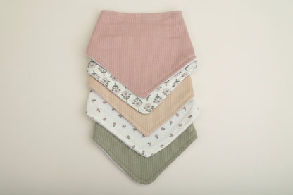 Set of 5 of colorful baby bibs on a warm white background.