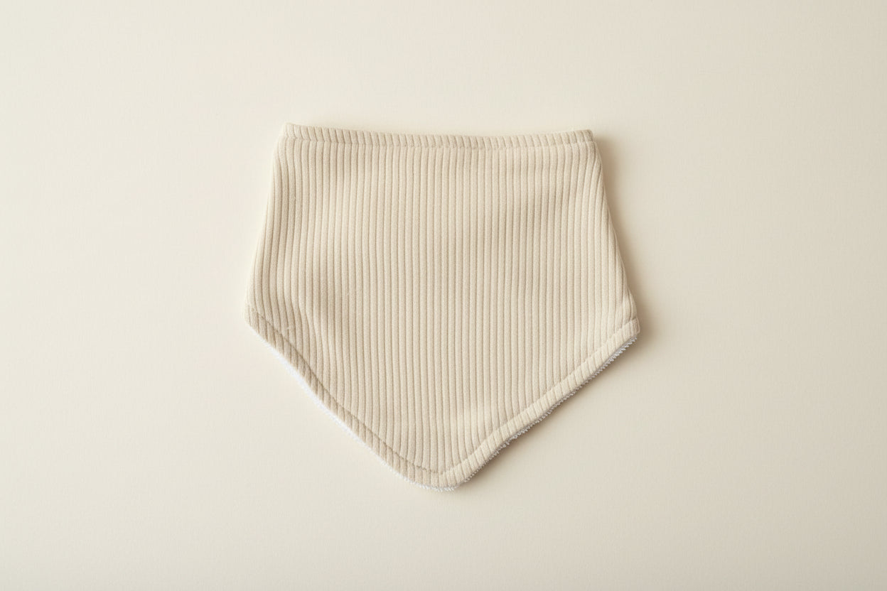 green baby bib on a warm white background.