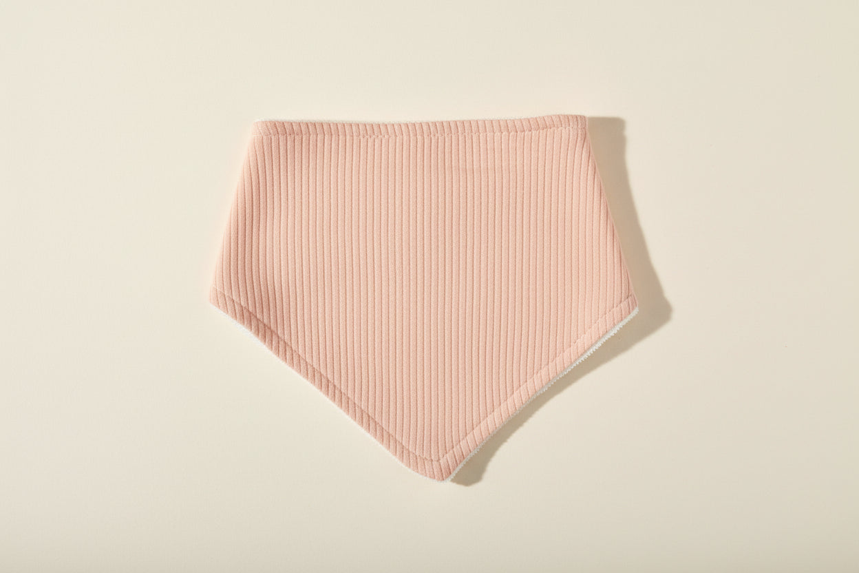 pink baby bib on a warm white background.