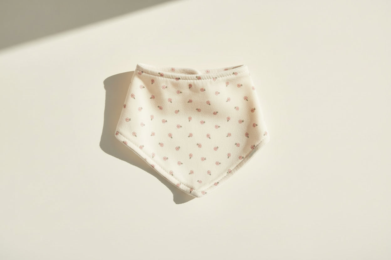 White baby bib with small floral pattern on a warm white background