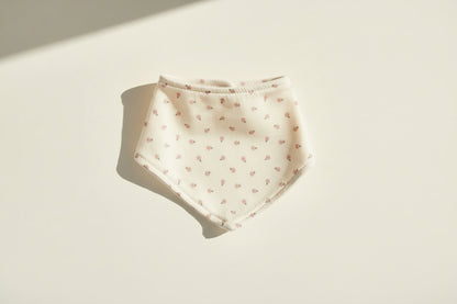 White baby bib with small floral pattern on a warm white background