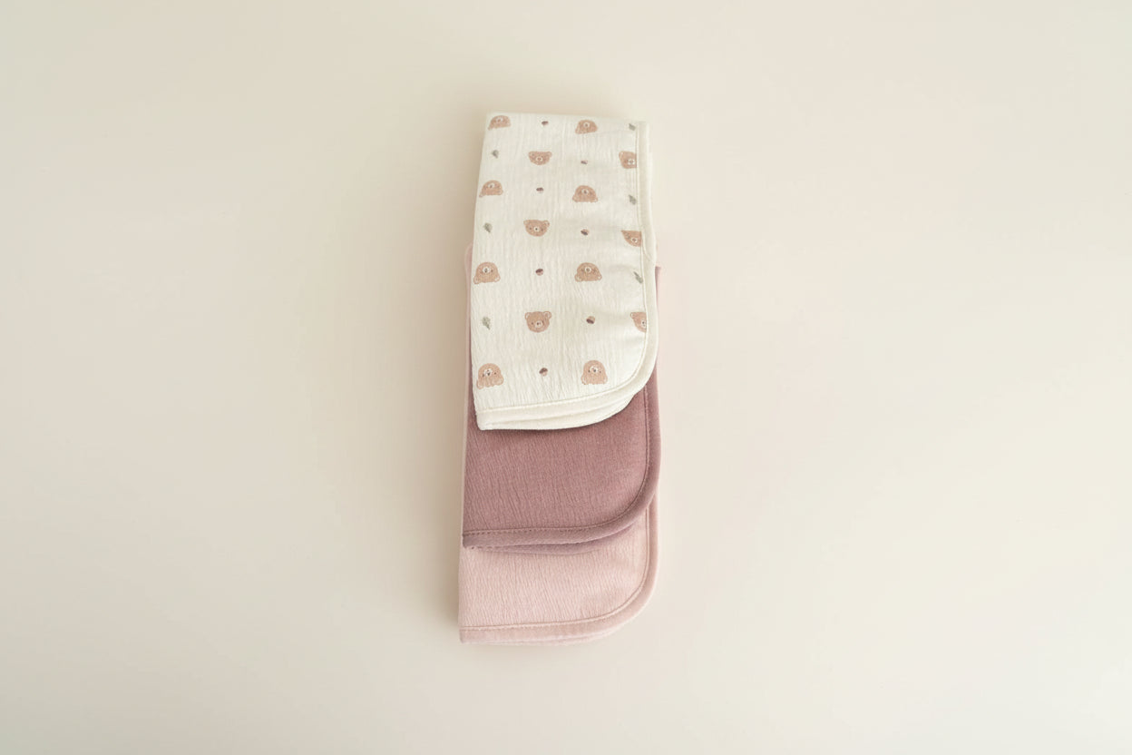 Set of three baby burp cloths in different patterns and colors.