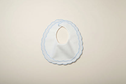 White bib with blue trim on a beige surface