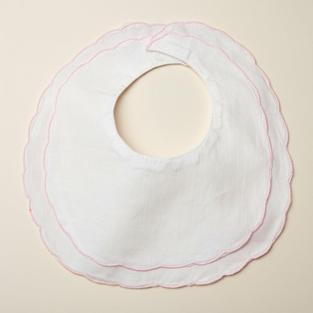 White bib with pink stitching on a beige surface