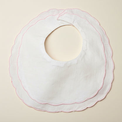 White bib with pink stitching on a beige surface
