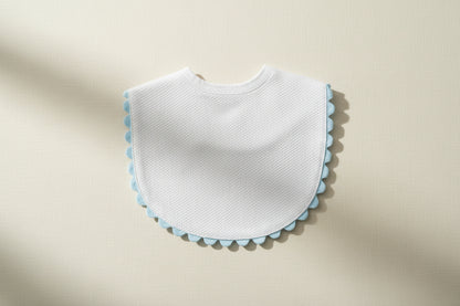 White bib with blue trim on a wooden surface