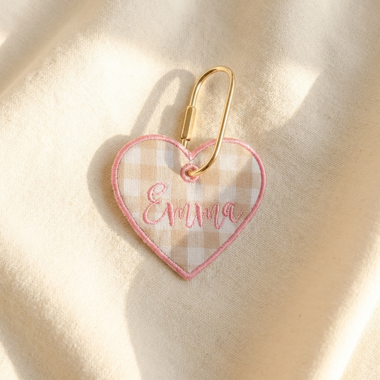 Heart-shaped keychain with 'Emma' embroidery on a beige background