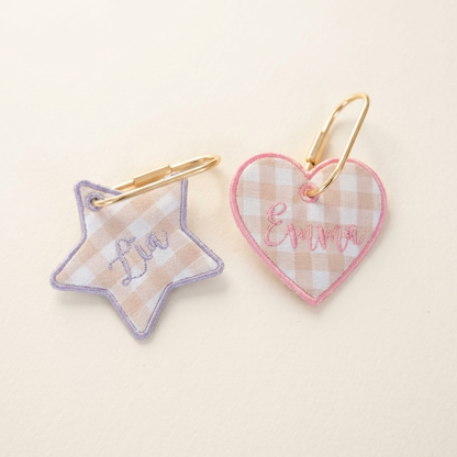 Star and heart keychains with embroidered names on a light beige background