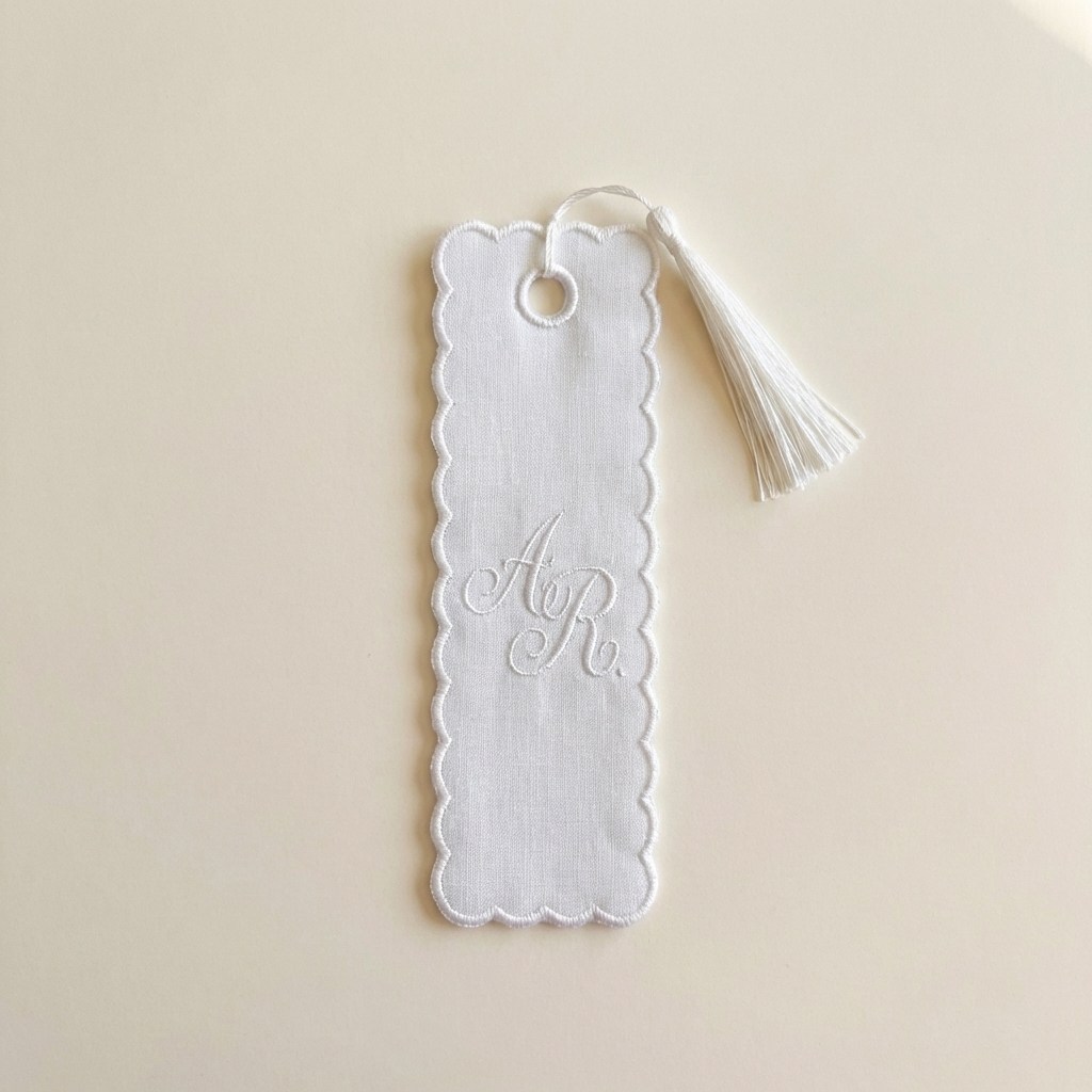 White scalloped bookmark with tassel on a beige background