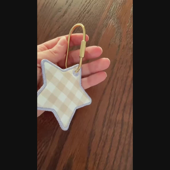 Video of star shaped embroidered keychain / bag tag on wooden surface