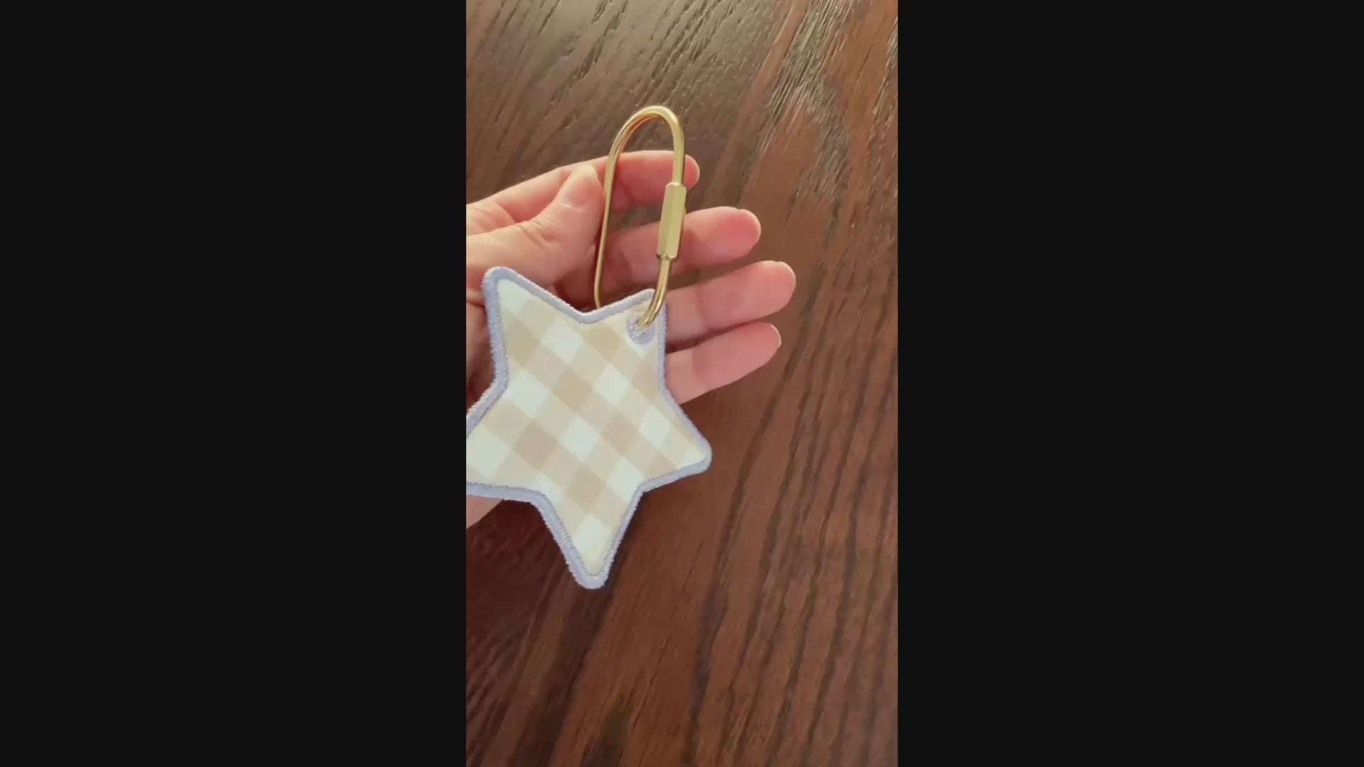 Video of star shaped embroidered keychain / bag tag on wooden surface