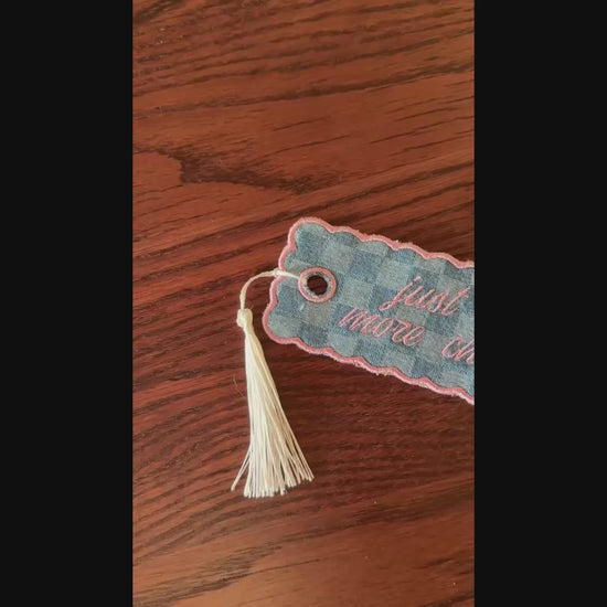 embroidered bookmark on a wooden surface.