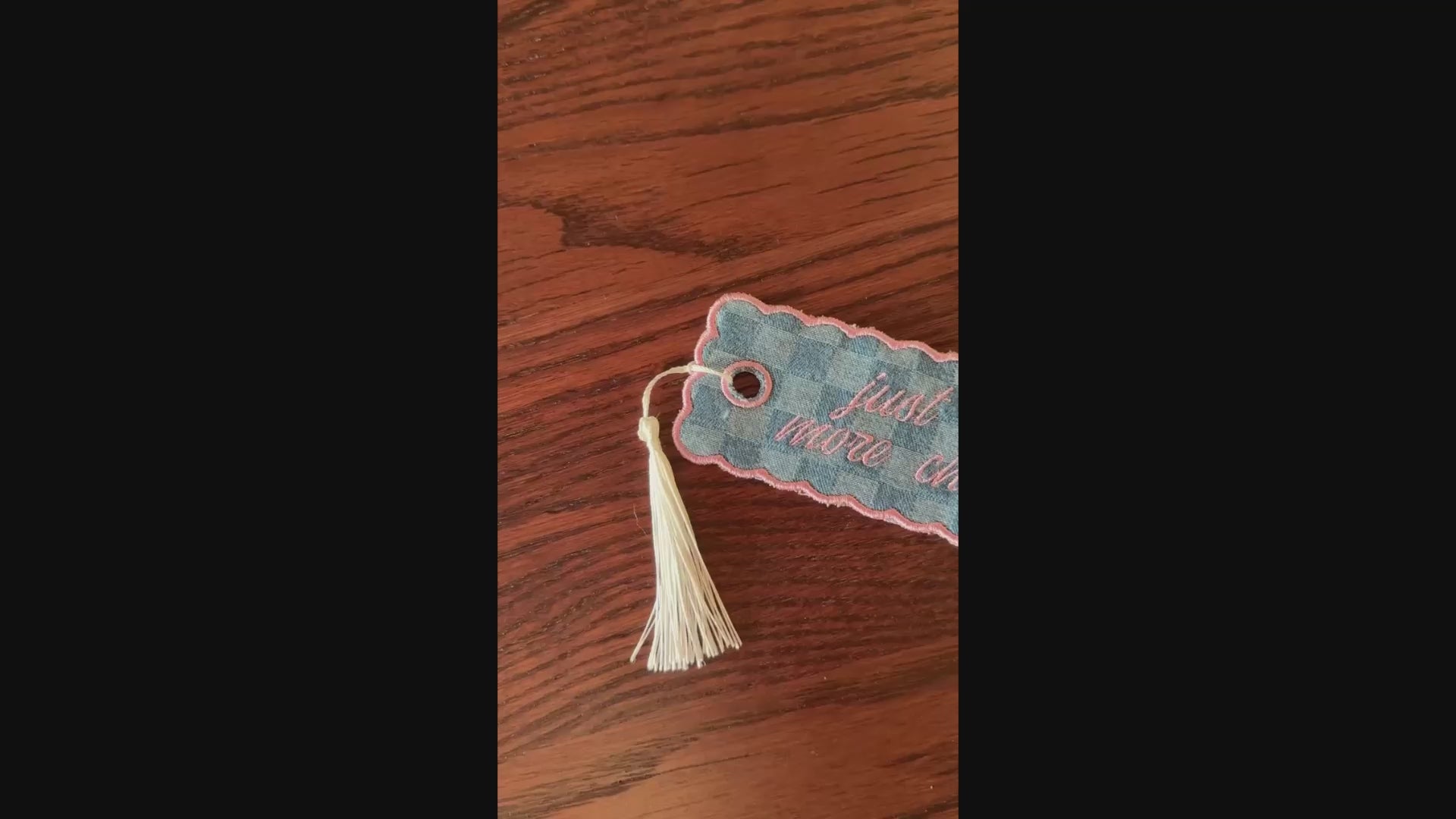embroidered bookmark on a wooden surface.
